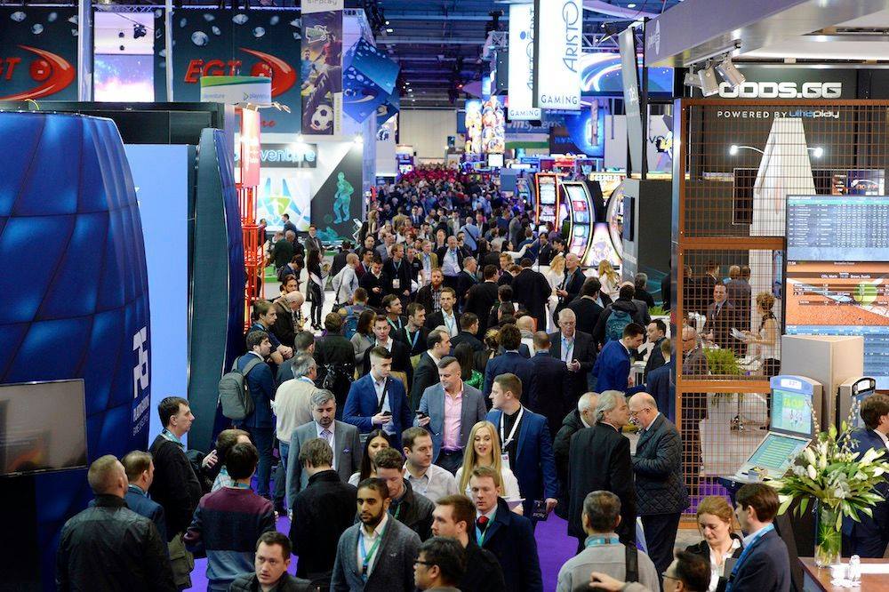 Crowds of attendees filling the aisles between gaming booths at the ICE London 2019 expo floor.