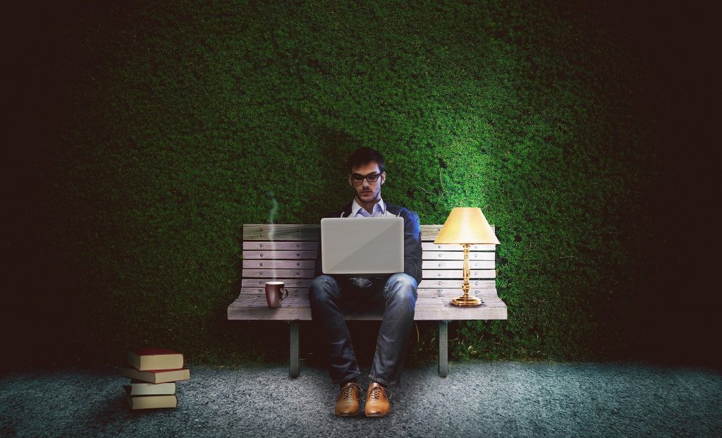 A man working on a laptop on a bench with a lamp and coffee, illustrating tips for hiring a casino writer.