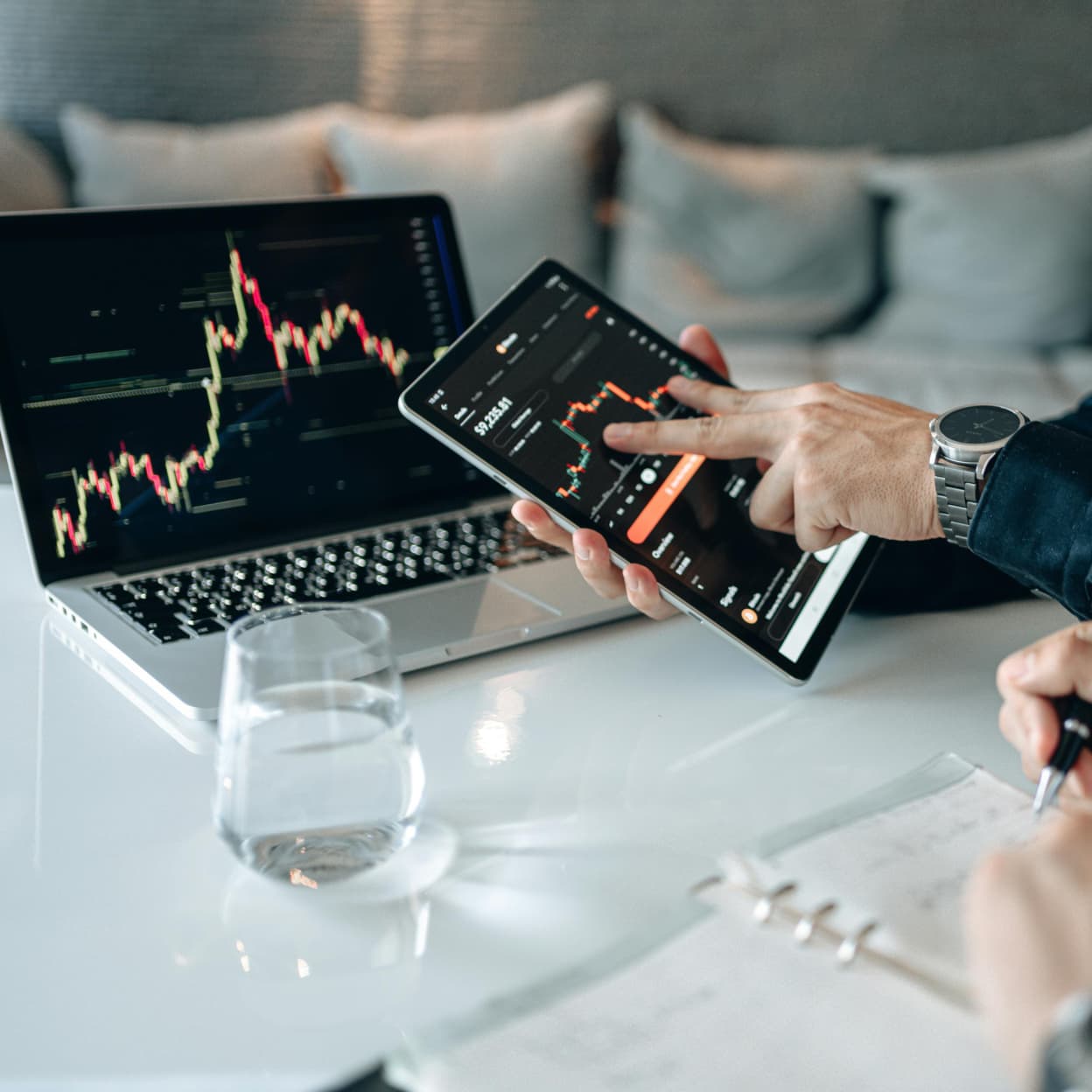 A person analysing trading charts on a tablet and laptop, illustrating finance writing services.