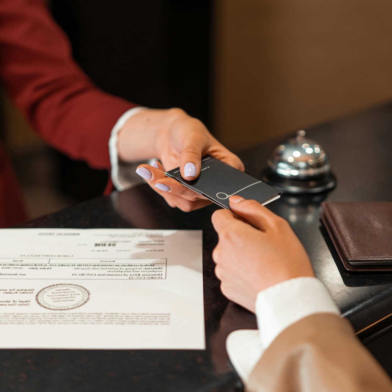 A hotel receptionist handing a keycard to a guest at the front desk, illustrating hospitality writing.