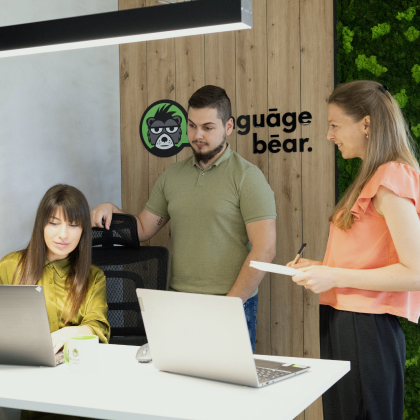 Projektmanager von Language Bear arbeiten mit einem Kollegen am Schreibtisch im Büro zusammen.