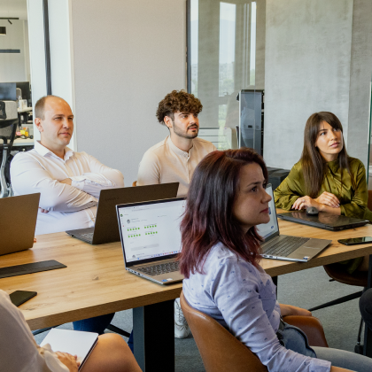 Das Language-Bear-Team arbeitet mit Laptops an einem Tisch in einem hellen, modernen Büro zusammen.