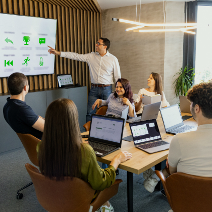 Teammeeting bei Language Bear: Ein Kollege präsentiert der Gruppe am Tisch.