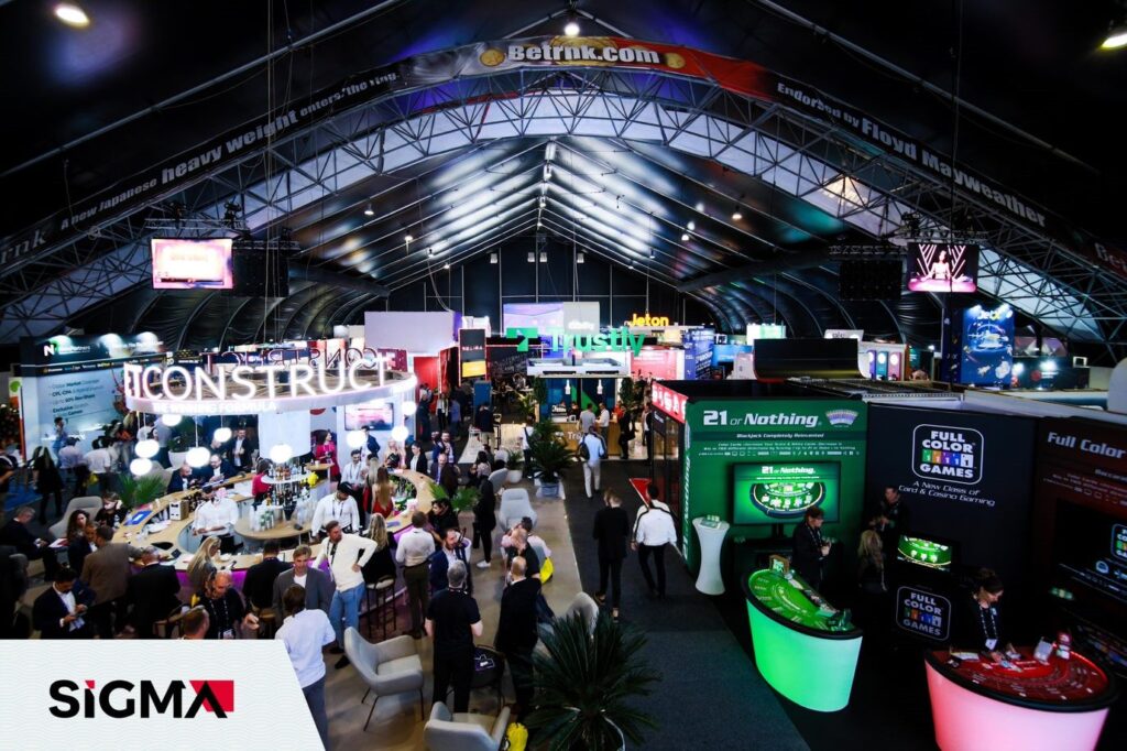 An elevated view of the SiGMA Europe 2021 show floor with a bar and lit gaming booths and crowds.