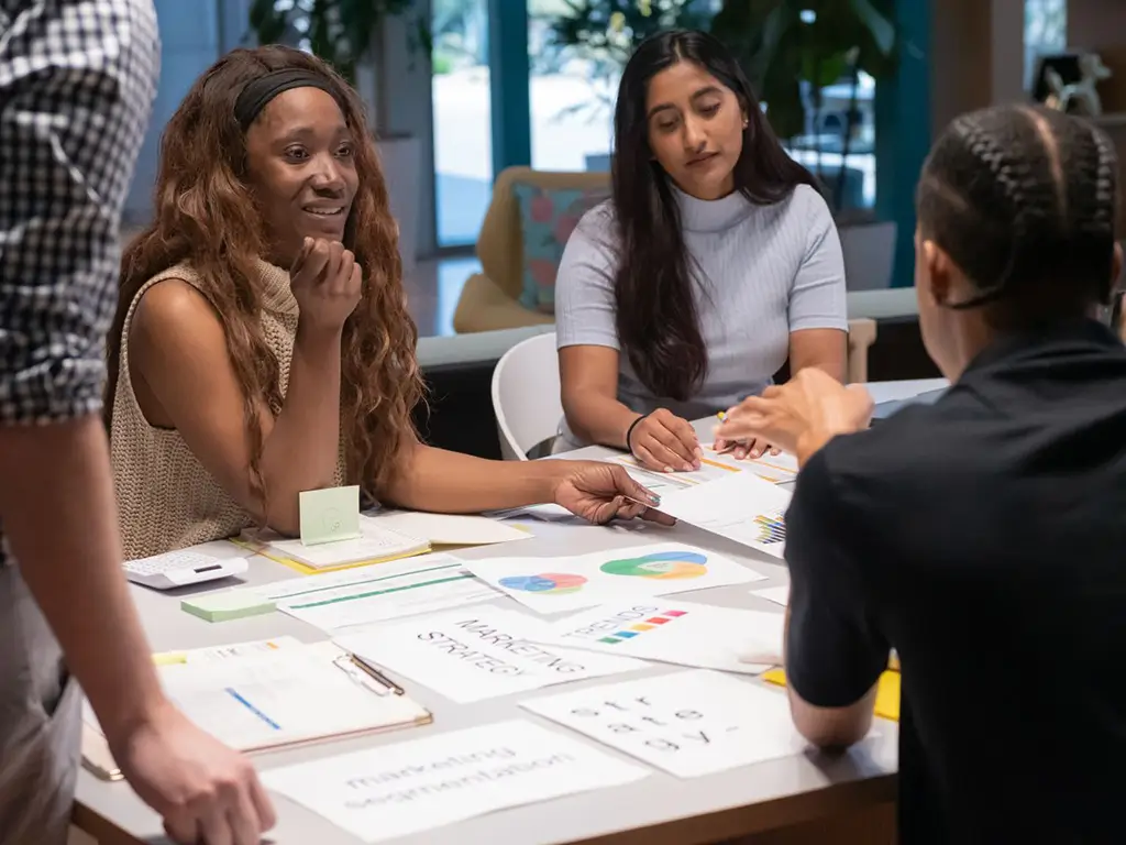 A team reviewing marketing strategy charts around a table, illustrating marketing translation services.