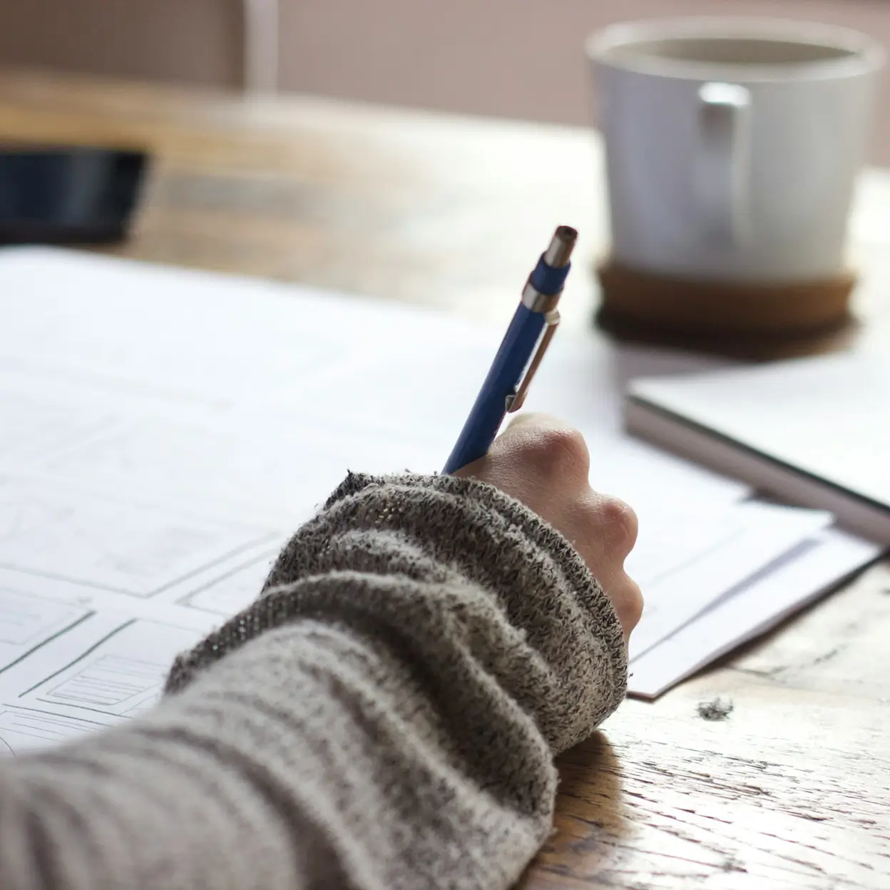 Close-up of an editor's hand correcting a printed draft with a pen, illustrating professional proofreading services.